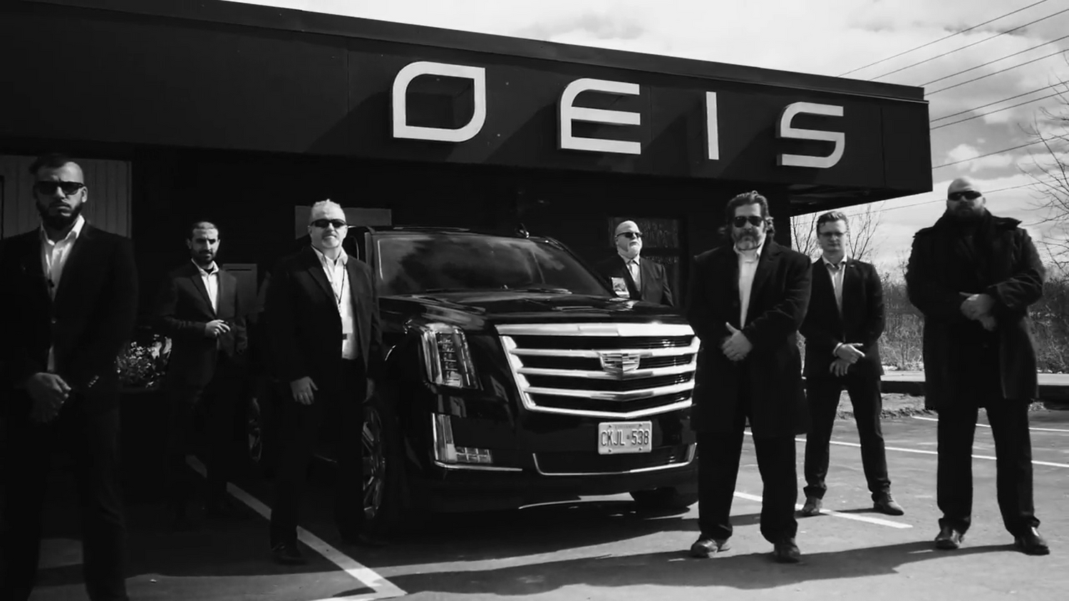 OEIS Private Investigations and Security team in black suits. They are standing at the Head Office Location in Niagara Falls with a fully equipped Black Cadillac. 